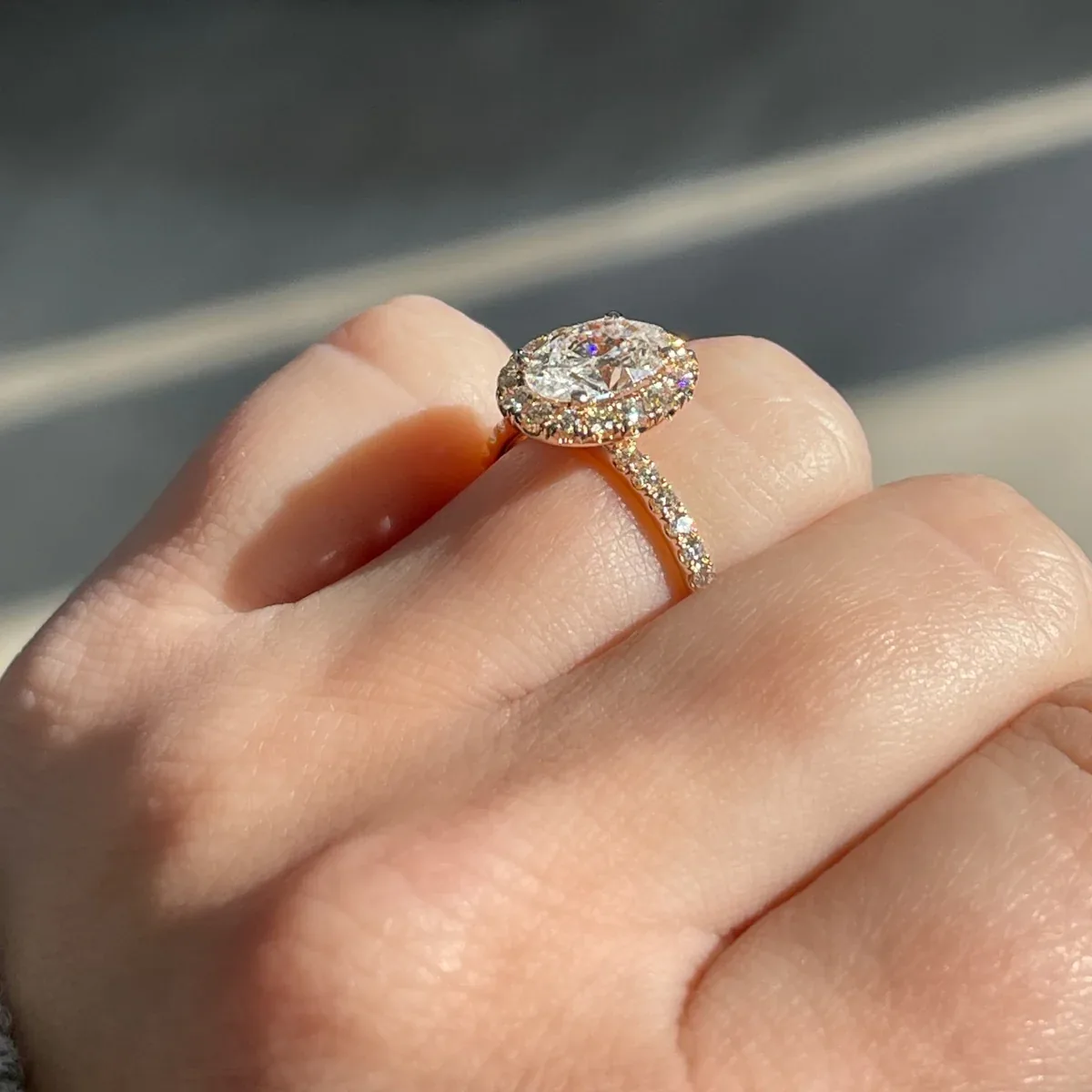 Rose gold oval halo ring modeled on a hand