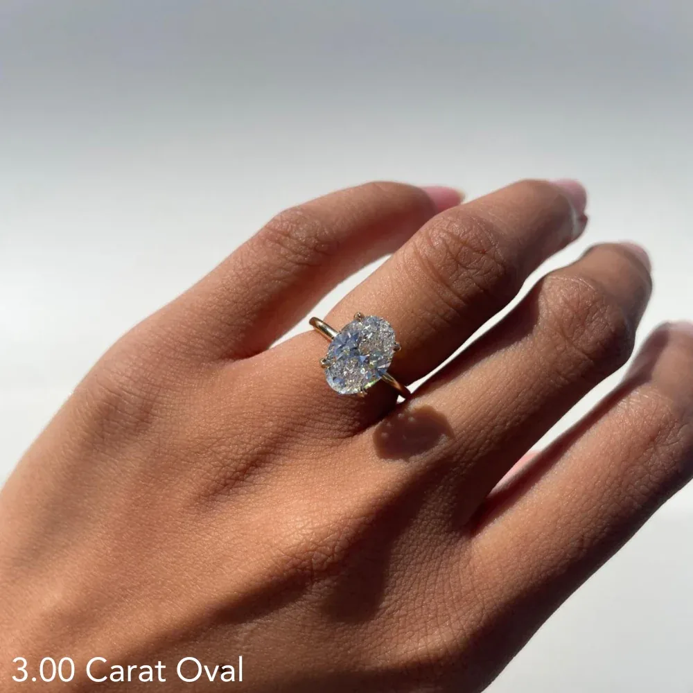 Oval yellow-gold solitaire engagement ring modeled on a hand